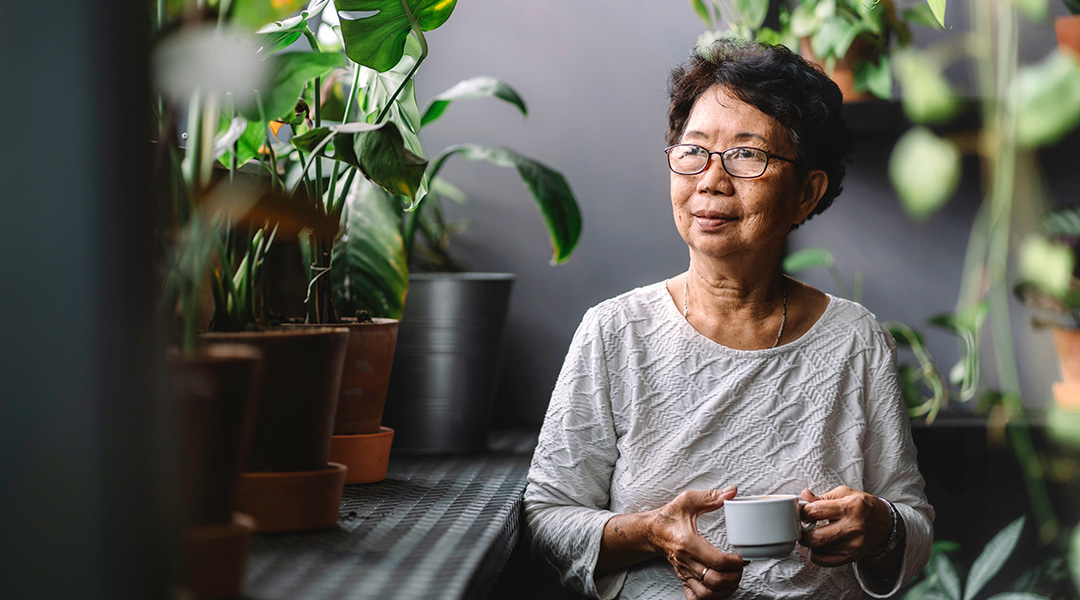 An older lady of asian decent wearig glasses looking to her right towards a bright window